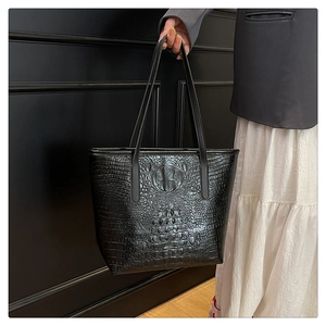 Close-up of black crocodile-embossed leather tote bag with elegant texture and sturdy handles
