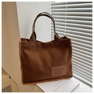 Detail of brown corduroy tote bag showing vertical striped texture and handle