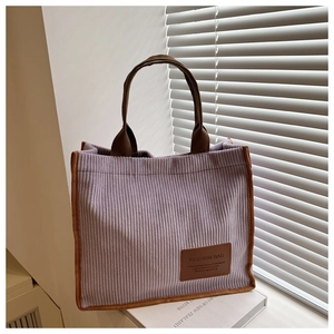 Detail of purple corduroy tote bag with brown trim and fashion leather label