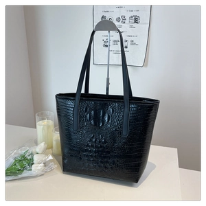 Close-up of black crocodile pattern faux leather tote bag with glossy finish and long straps