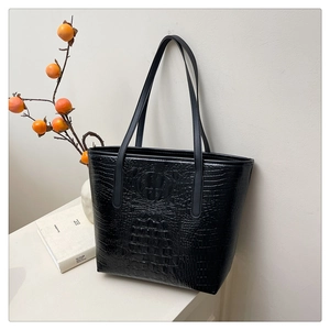 Macro detail of high-quality black crocodile pattern embossing on a tote bag surface