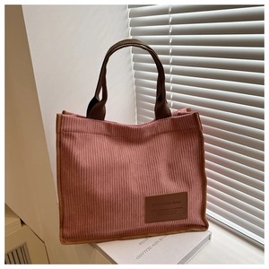 Detail showing pink corduroy texture and brown woven handles of a fashion tote bag