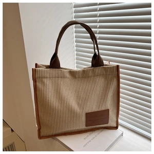 Detail of corduroy tote bag featuring leather brand patch and brown contrast stitching