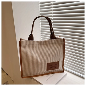 Detail of corduroy tote bag with striped texture, contrast trim and fashion leather patch