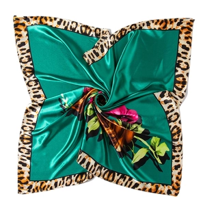 Détail d'un foulard en satin soyeux avec centre vert, fleurs roses et bordure léopard