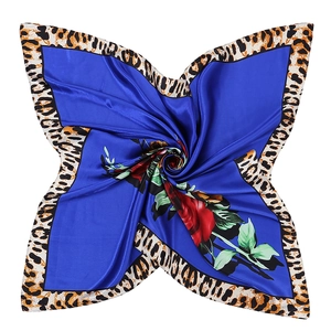Détail macro du foulard en soie bleu roi avec bordure léopard et motifs roses rouges