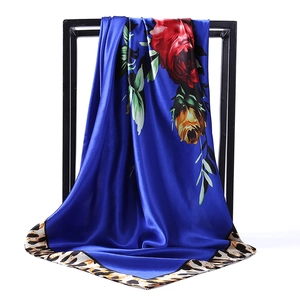 Détail d'un foulard en satin bleu roi avec roses rouges et bordures imprimé léopard