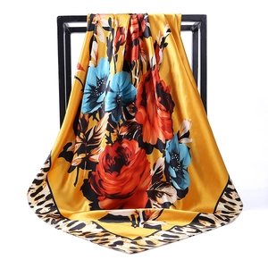 Détail d'un foulard en soie jaune avec imprimés roses et bordures léopard classiques
