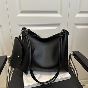 Black large leather tote bag with rope shoulder strap and small pouch on modern chair