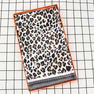 Élégant foulard en soie léopard 90cm plié dans une boîte orange sur une nappe