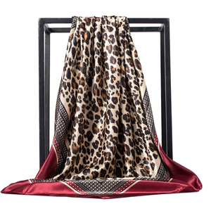 Détail d'un foulard en soie à motif léopard et bordure bordeaux sur un cadre noir