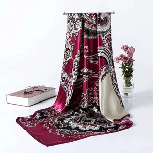 Detail view of burgundy paisley satin scarf draped on a metal stand with floral decor