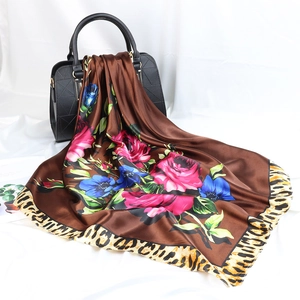 Carré de soie à fleurs avec bordure léopard drapé sur un sac à main noir chic
