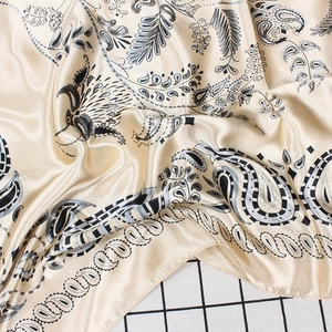 Dettaglio del tessuto della sciarpa in raso paisley color oro champagne e finitura lucida