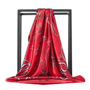 Dettaglio di sciarpa in raso rosso con motivo paisley e consistenza setosa fluente