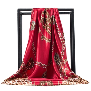 Detailed texture of red satin silk scarf with golden chain and leopard print patterns