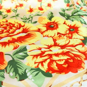 Detail of satin floral scarf showing vibrant orange flowers and gold chain pattern texture