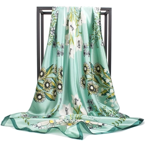 Détail du foulard en satin de soie avec motifs floraux vert menthe et tournesols
