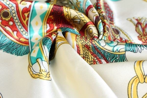 Detailed macro view of luxurious silk scarf with gold chain and equestrian prints