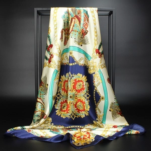 Detail of luxury silk scarf featuring golden chain print and elegant tassel patterns