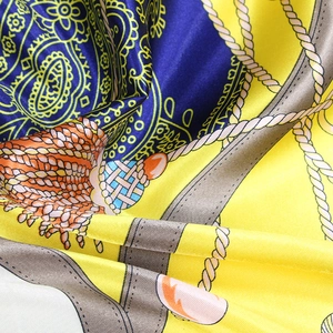 Detailed close-up of yellow silk scarf with nautical rope and paisley patterns