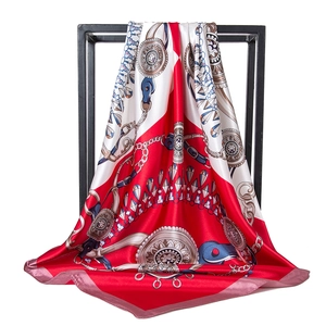 Close-up of red and white silk scarf with vintage gold chain prints and medal patterns