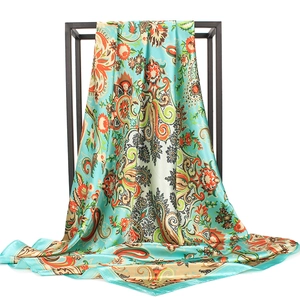 Detail of mint green paisley silk scarf draped over a black metal display frame