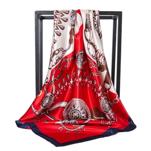 Detailed close-up of 90cm satin scarf with golden chain print and red blue border
