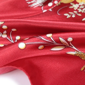 Detailed macro view of red floral silk scarf featuring vibrant botanical berry prints