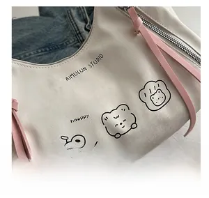 Close-up of a white leather tote bag featuring a cute cartoon bear print and pink zipper