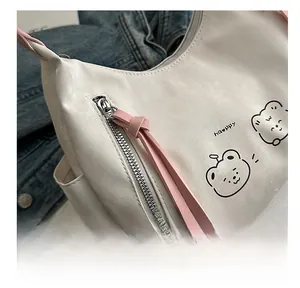 Detail of white leather tote with cute bear illustration and pink charm accessory