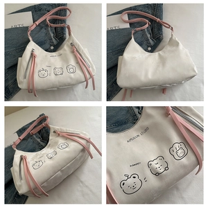Detail view showing white crescent bag with bear illustration and pink shoulder strap