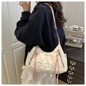 Detail of cream shoulder bag with pink straps featuring cute cartoon bears and zipper tassels