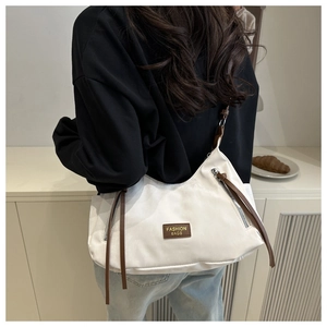 Vue latérale détaillée du sac bandoulière en toile blanc cassé avec sangle en cuir marron
