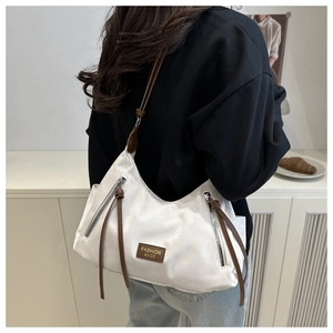 Détail du sac cabas blanc avec lanières en cuir brun et doubles zips verticaux