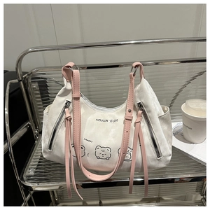 Détail d'un sac cabas blanc avec dessins d'animaux et bandoulières en cuir rose sur support