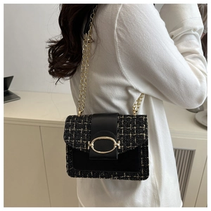 Détail du sac bandoulière en tweed noir avec chaîne dorée porté par un mannequin