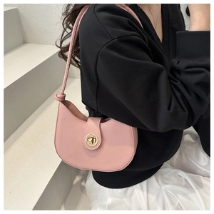 Détail du sac demi-lune rose avec fermoir doré tournant et bandoulière à nœud élégante