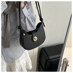 Detail of black half-moon shoulder bag with golden ring buckle and adjustable strap