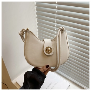 Détail d'un sac demi-lune blanc crème avec fermoir doré et bandoulière à nœuds élégante