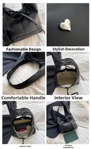 Detail of black leather tote bag showing heart buckle, bow tie and spacious interior