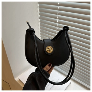 Détail du sac demi-lune en cuir noir avec fermoir doré rotatif et bandoulière à nœuds