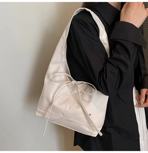 Detail of the oversized bow decoration on a creamy white leather shoulder tote bag