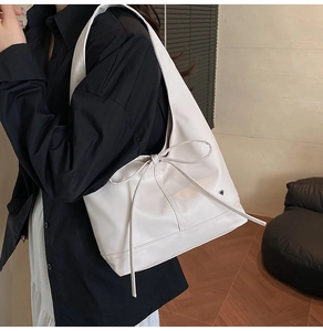 Detail of the white nylon tote bag with decorative bow and small heart-shaped metal emblem