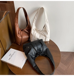 Three minimalist leather hobo bags in black, white, and brown with decorative bows
