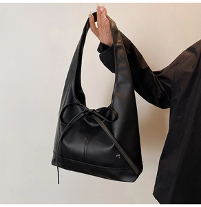 Détail du sac hobo noir avec un grand nœud et une étiquette métallique en forme de cœur