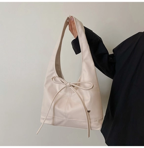 Détail du sac Hobo beige avec un grand nœud décoratif et un petit pendentif en forme de cœur
