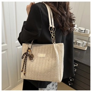 Detail of woven straw bucket bag with white leather straps and tennis racket charm