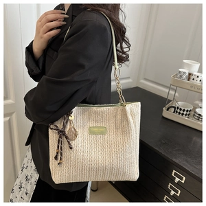 Detail of woven tote bag with green trim, striped ribbon and golden tennis racket charm