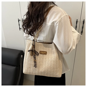Detail of H-weave straw tote bag with leather gold chain strap and brand leather patch